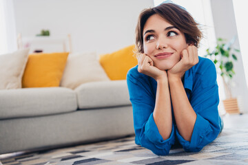 Photo of dreamy adorable cute girl lying on carpet in cozy living room enjoying harmony indoors