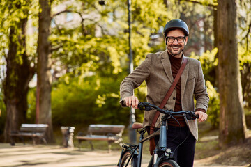 Portrait of a smiling businessman pushing a bicycle while going to work.