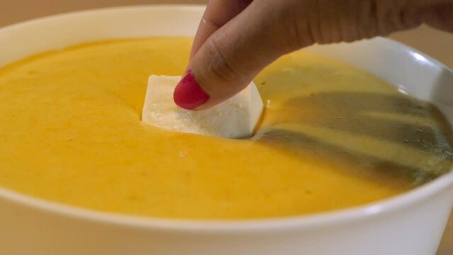 Closeup shot of Indian snack paneer pakora served during breakfast or tea time. Hand of a woman dipping a piece of paneer in gram flour/besan batter to make fresh paneer pakora's at home