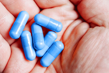 Medicine background. Blue pills isolated on white. Pile of capsules. Tablets background. Vibrant vivid color drugs. Antibiotics background. Holding blue pills. Drugs on hand. Diet supplementation.