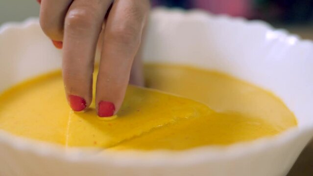 Woman's hand dipping stuffed bread in besan batter to make fresh bread pakora. Closeup shot of a popular Indian snack bread pakora served during breakfast time or tea time in India