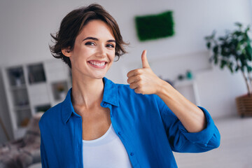 Portrait of positive gorgeous girl beaming smile arm finger demonstrate thumb up spacious apartment indoors - obrazy, fototapety, plakaty