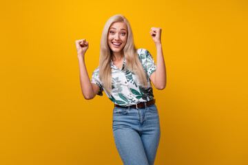 Portrait of overjoyed girl with long hairstyle wear flower print blouse raising fists up win...