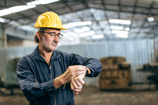 Engineer worker worry looking at wristwatch working time clock. Industry factory late working hours concept.
