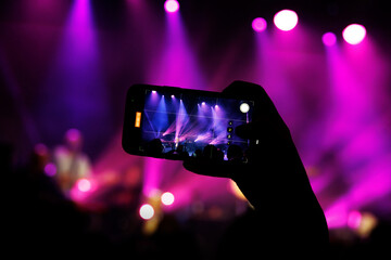 A concert-goer captures the live performance of a band on their phone