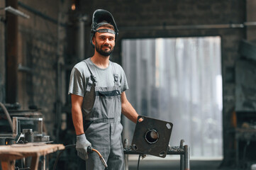 Fototapeta na wymiar Welder man in safety helmet. Young factory worker in grey uniform