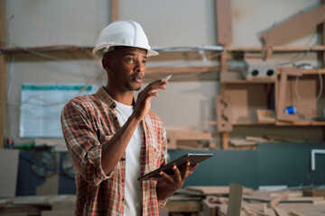 African male uses tablet to check stock in carpentry factory 