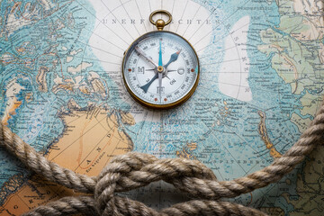 Magnetic old compass and rope on old nord pole map. Travel, geography, history, navigation, tourism and exploration concept background. Retro compass on geography map.