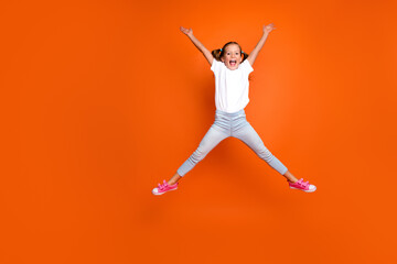 Fototapeta na wymiar Full size portrait of active overjoyed girl jump make star figure empty space isolated on orange color background