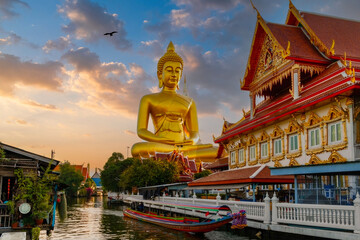 Fototapeta premium Golden Hour at Thai Temple with Colossal Buddha Statue, Traditional Long-Tail Boat, and Serene River Scene