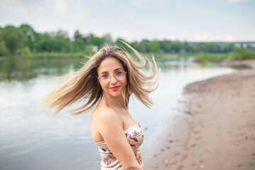 glückliche junge Frau mit wehenden Haaren steht am Fluss