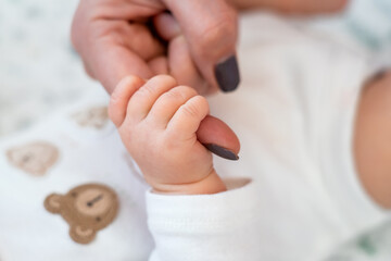 Newborn baby tiny hand holds finger of mother