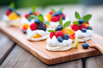 mini pavlovas with whipped cream on a wooden board - obrazy, fototapety, plakaty