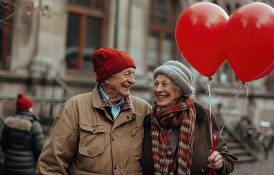 Happy senior couple holding hearted balloons