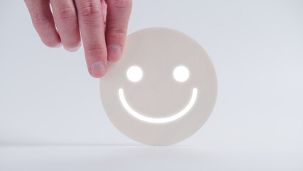 Customer service evaluation and satisfaction survey concepts. The client's hand picked the happy face smile face icon on circle wood