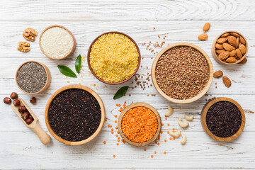 Various superfoods in smal bowl on colored background. Superfood as rice, chia, quinoa, lentils, nuts, sesame seeds, almonds. top view copy space - obrazy, fototapety, plakaty