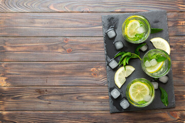 Caipirinha, Mojito cocktail, vodka or soda drink with lime, mint and straw on table background. Refreshing beverage with mint and lime in glass top view flat lay - obrazy, fototapety, plakaty