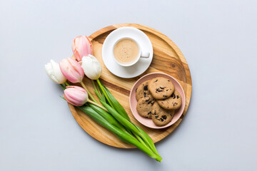 Cup of coffee mug with coffee, cookies and tulips on a colored background. Greeting spring card top view