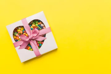 Tuinposter Box with sweet chocolate candies on color background, Various candy sweets. Valentines day gift box. Top view flat lay with copy space © sosiukin