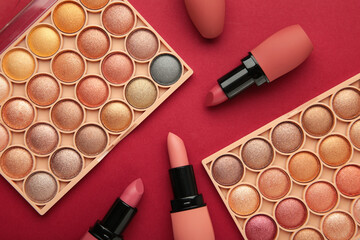 Colorful lipsticks and palette shadow on red background. Makeup
