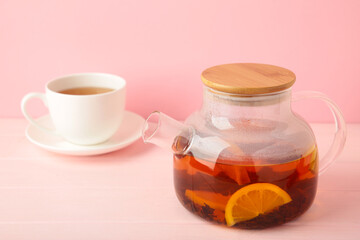 Glass teapot and cup on pink background.