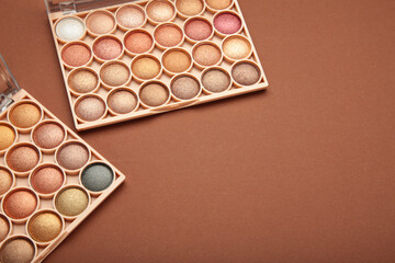 Pastel palette of eyeshadow on brown background. Space for text