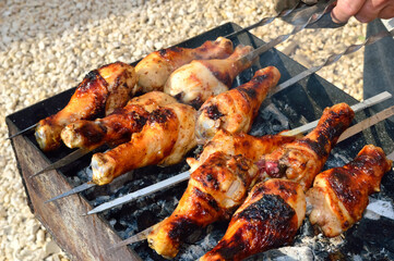close-up - cooking chicken drumsticks barbecue on sticks on the grill