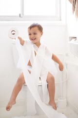 Boy child, potty training and toilet paper with sitting, mummy and thinking for learning,...