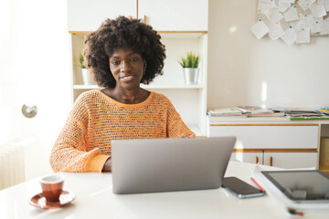 Smiling woman using laptop at table in home office
