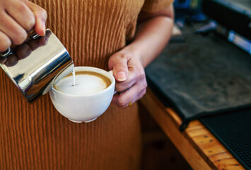 Barista pouring milk into coffee making a cappuccino. Barista making cappuccino,Professional bartender preparing coffee drink