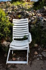 broken white plastic chair discarded on a rubbish bin for garbage collection