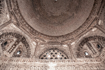 Dome and sophisticated wall decorations of raw bricks. Interior of Samanid Mausoleum, medieval masterpiece (IX-X c. AD). Monochrome. April 18, 2023. Bukhara, Uzbekistan - obrazy, fototapety, plakaty