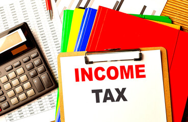 INCOME TAX text written on paper clipboard with chart and calculator