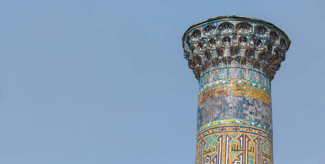 Sher Dor Madrasah flanking minaret with light blue sky at background. Banner, copy space. Registan square, Samarkand, Uzbekistan