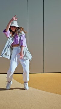 Young hip hop girl in oversize outfit wearing dancing into music minimalistic urban background. Hip-hop queen. Breakdancer woman. minimalistic 