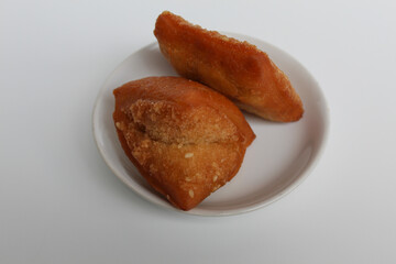 Odading or Bolang-Baling or Pillow Cake, sweet fried bread with sesame seed on top, from Indonesia. On a small plate isolated on background