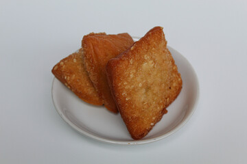 Odading or Bolang-Baling or Pillow Cake, sweet fried bread with sesame seed on top, from Indonesia. On a small plate isolated on background