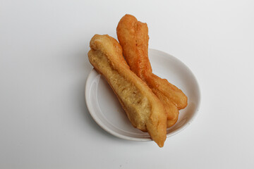Cakwe or cakue, fried savory cake from Indonesia, on small white plate, isolated on white background
