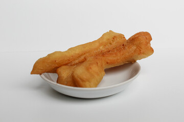 Cakwe or cakue, fried savory cake from Indonesia, on small white plate, isolated on white background