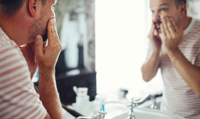 Millennial handsome man looking in mirror, applying moisturizing washing cream