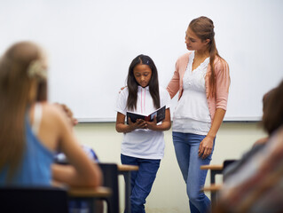 Presentation, class and teacher with book to read in front for classmates, ready and learning. Elementary school, girl and prepared oral with workbook, childhood development and academic education