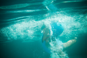 Little girl swims in the pool underwater - obrazy, fototapety, plakaty