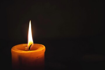 Fototapeta na wymiar Candle flame flickering in a dark room