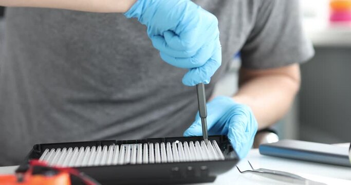 Male repairman repairing lighting equipment with oled lamps closeup. Engineer with a screwdriver collects appliances concept