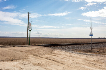 Train tracks crossing dirt road in middle of remote farmland - 707093142