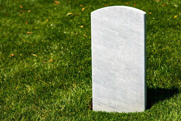 A white marble tombstone on a grassy lawn at Arlington National Cemetery, a military cemetery in...