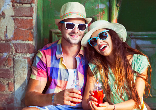 Happy young couple in the street wearing hats and sunglasses