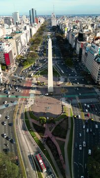Vertical Aerial drone view of Buenos Aires obelisk on avenida de Julio in Buenos Aires, Argentina. Shows buildings and skyscrapers with car traffic in the Street below.
