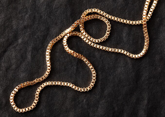Gold chain on black silk fabric. Close-up