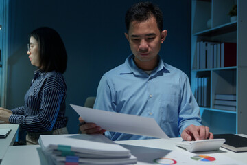 Young Asian businessman uses a calculator to analyze financial data, marketing, balance sheets, net profits, taxes to plan sales strategies. Calculate the company's budget business management concept